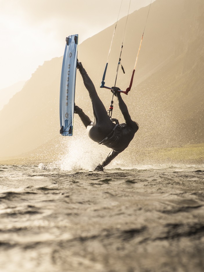 Kitesurfer in an ION wetsuit performing a trick in the waves