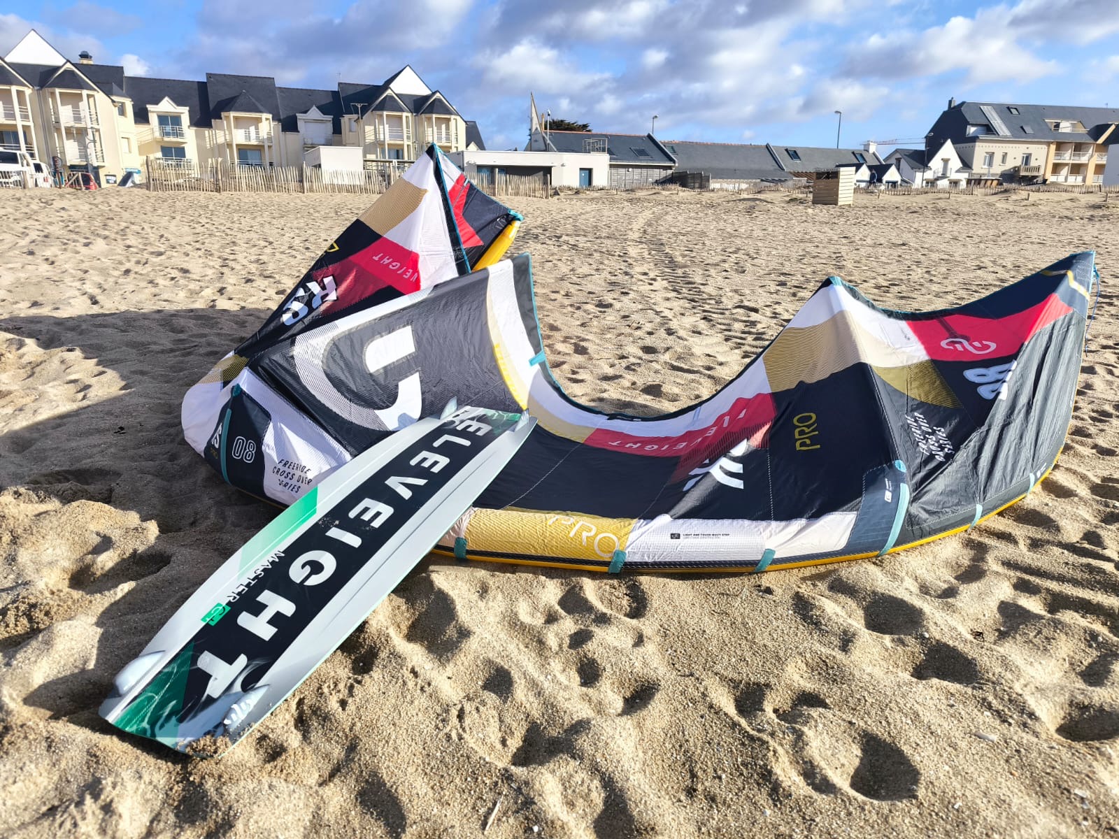 Aile de kitesurf Eleveight RS PRO V1 2025 posée sur le sable, avec des appartements en arrière-plan, aile performante pour freeride et big air.