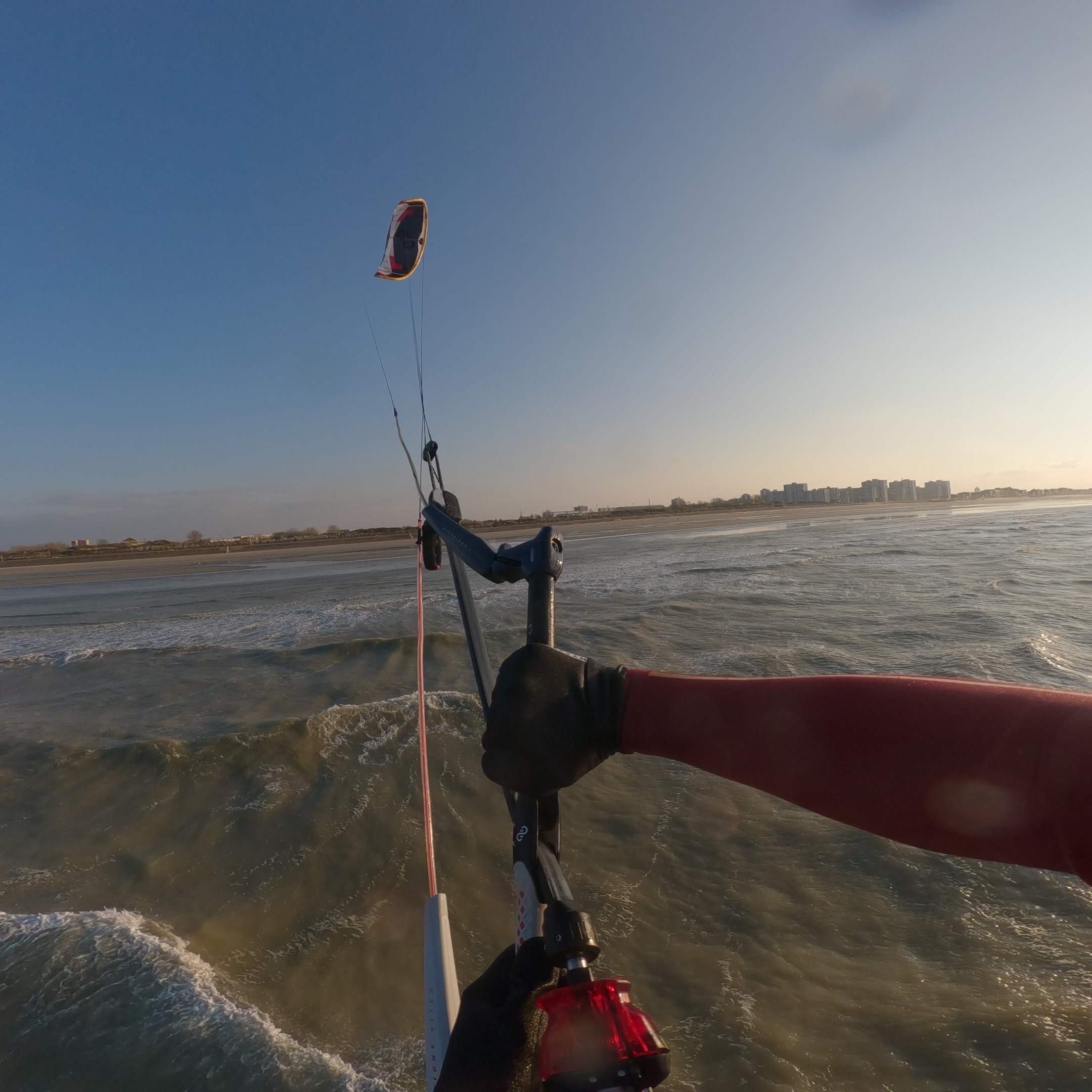 Rider en action sur une mer calme avec la barre de kite connectée à l’aile Eleveight RS PRO V1 2025, contrôle précis et performance en kitesurf.