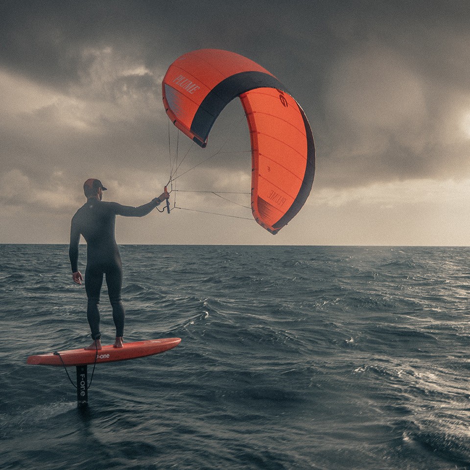 K-Wing foil sous un ciel orageux, pratique de la parawing avec planche rouge et aile assortie