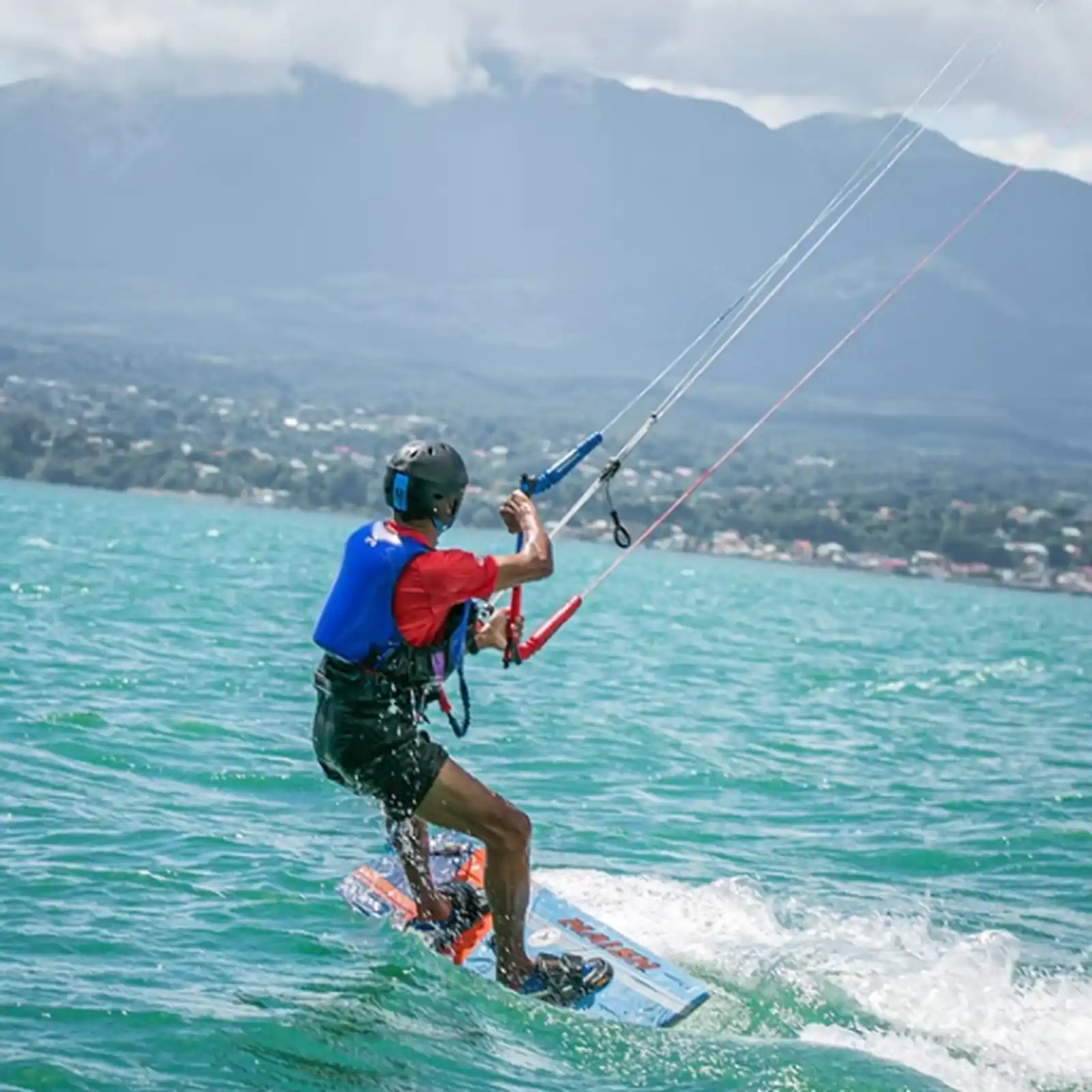 Kitesurfeur en progression sur un spot de Guadeloupe avec vue sur les montagnes